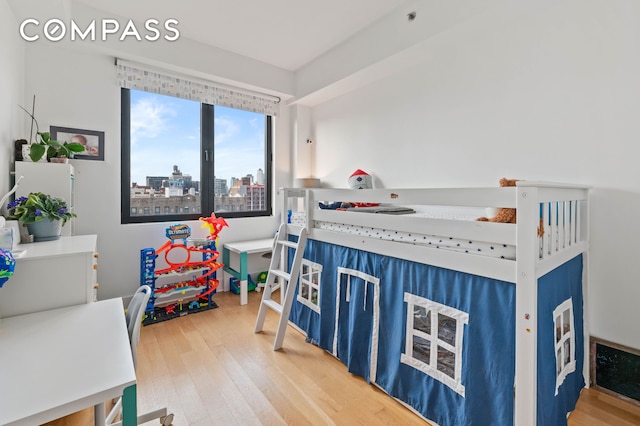 bedroom featuring a view of city and wood finished floors