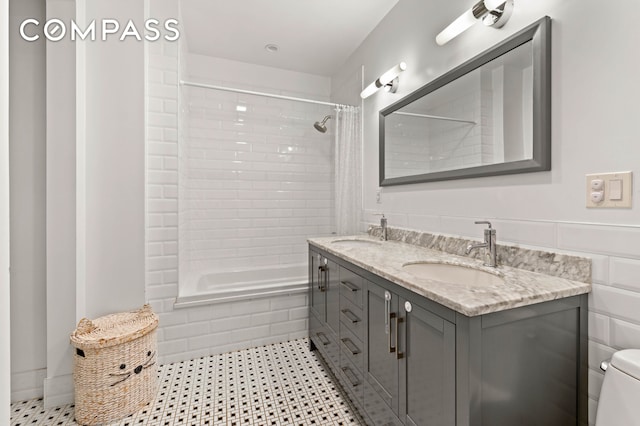 full bathroom featuring toilet, double vanity, a sink, and tiled shower / bath combo