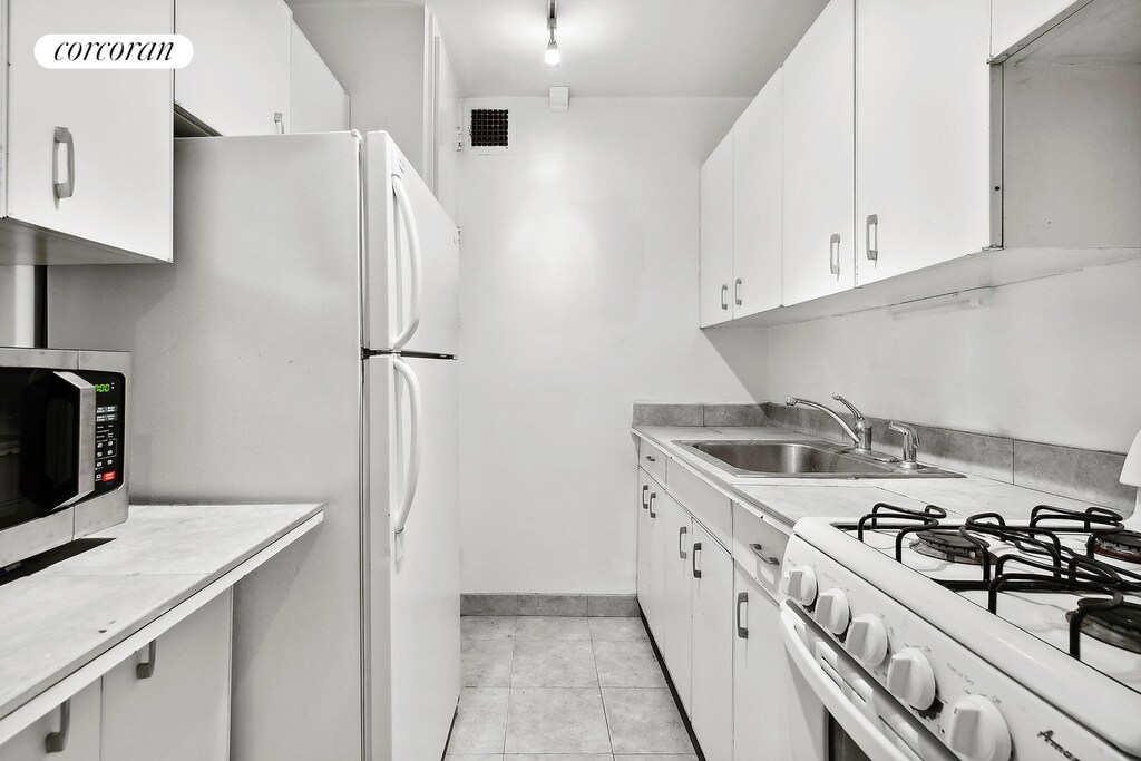 kitchen featuring sink, white appliances, and white cabinets