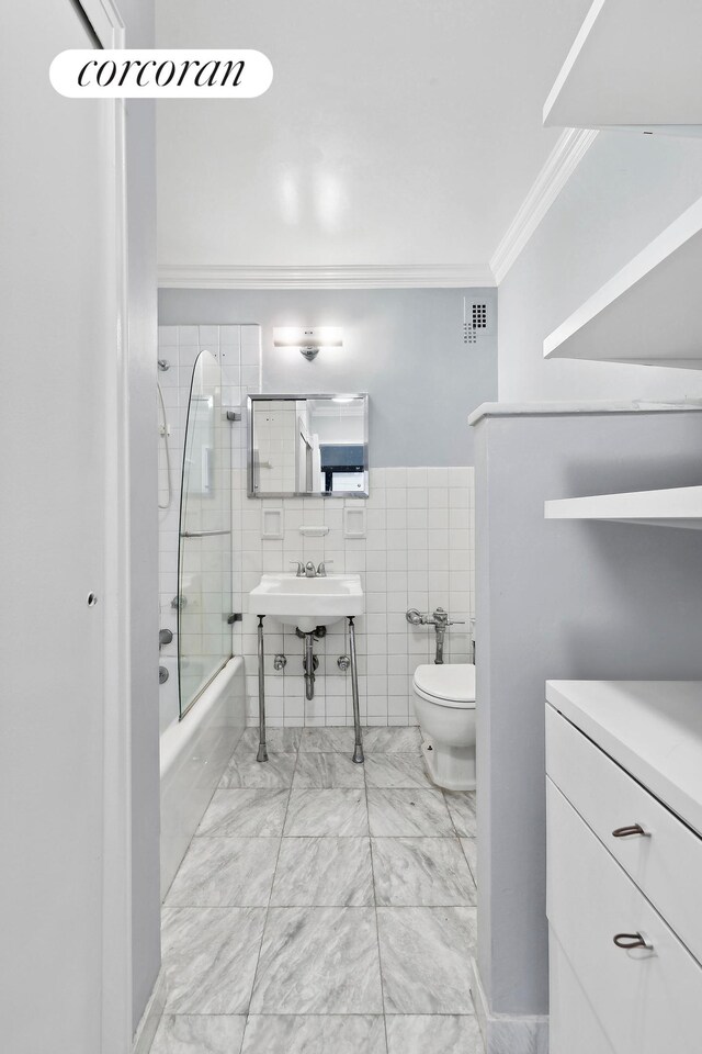 bathroom with crown molding, toilet, tiled shower / bath combo, and tile walls