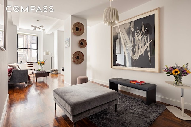 living area with an inviting chandelier, baseboards, and wood finished floors