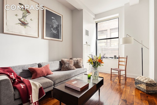 living room with wood finished floors, visible vents, and baseboards