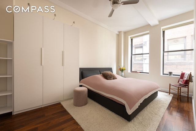 bedroom featuring beamed ceiling, dark wood finished floors, and a ceiling fan