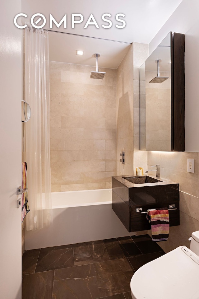 full bath featuring a combined bath / shower with rainfall shower, toilet, marble finish floor, tile walls, and vanity