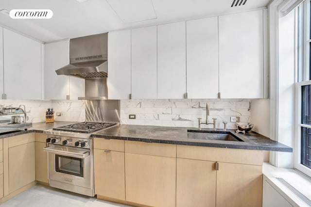 kitchen featuring visible vents, high end stainless steel range, decorative backsplash, wall chimney exhaust hood, and a sink