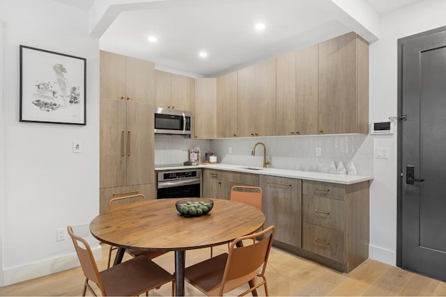 kitchen featuring sink, light hardwood / wood-style flooring, stainless steel appliances, decorative backsplash, and light brown cabinets