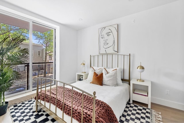 bedroom with hardwood / wood-style flooring, access to outside, and expansive windows