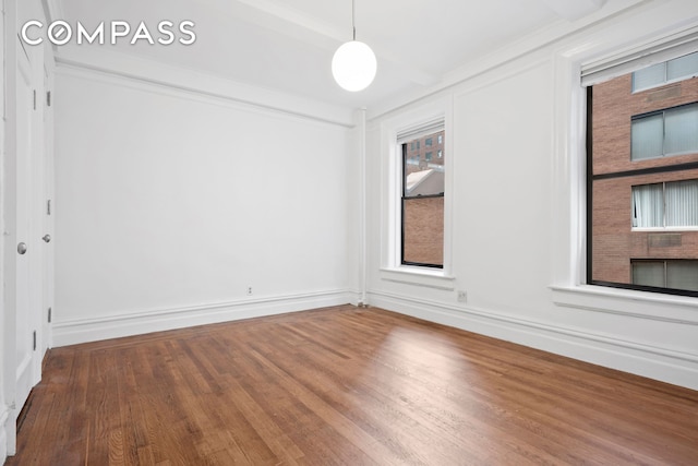 spare room featuring baseboards and wood finished floors