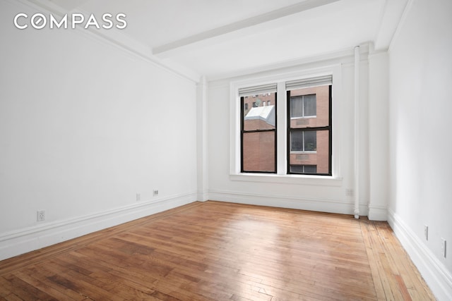 unfurnished room featuring beam ceiling, baseboards, and light wood-type flooring