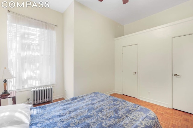 bedroom featuring radiator, ceiling fan, light parquet floors, and multiple windows