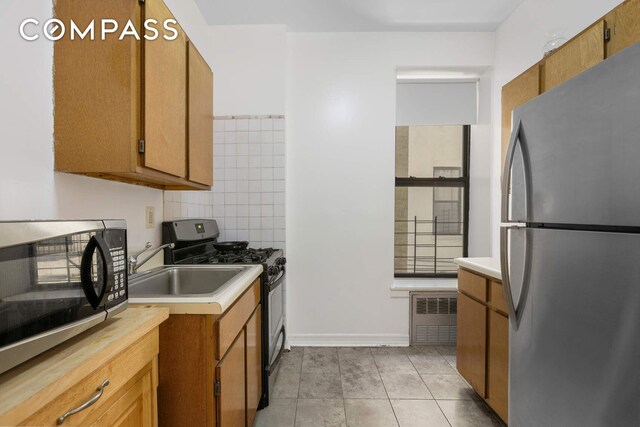 kitchen featuring light tile patterned flooring, appliances with stainless steel finishes, and tasteful backsplash