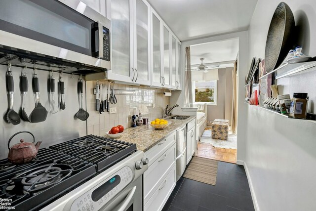 kitchen with sink, white cabinetry, stainless steel appliances, light stone counters, and decorative backsplash