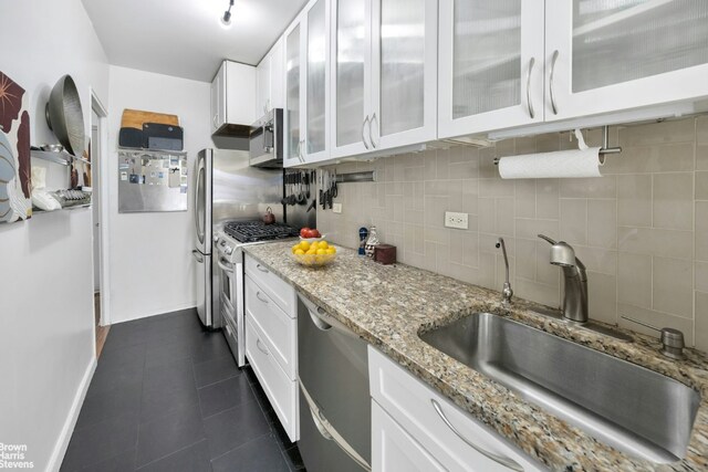 kitchen featuring sink, white cabinetry, light stone counters, appliances with stainless steel finishes, and decorative backsplash