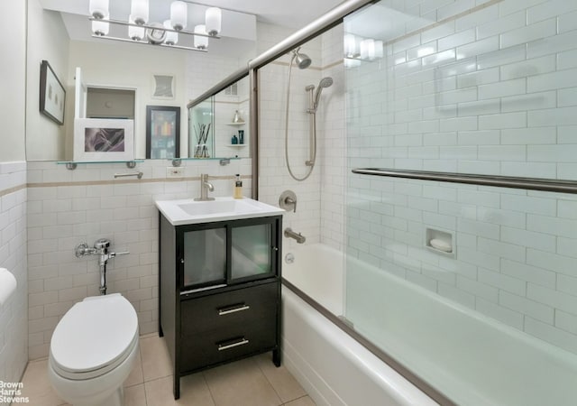 full bathroom with tile walls, tile patterned flooring, enclosed tub / shower combo, vanity, and toilet