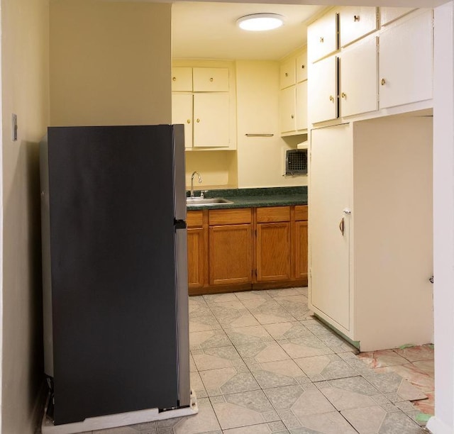 kitchen with sink, stainless steel fridge, and white cabinets