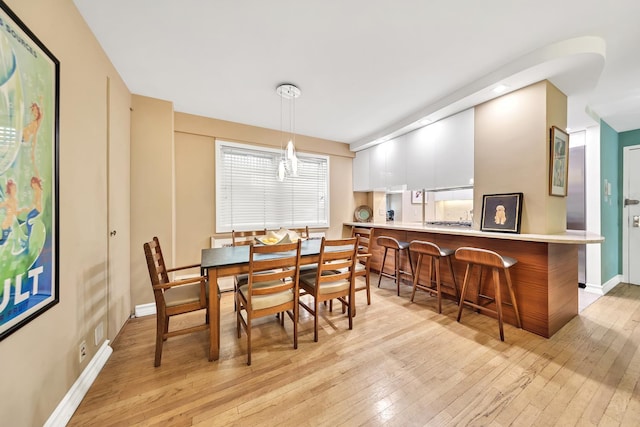 dining space with light wood-style flooring and baseboards