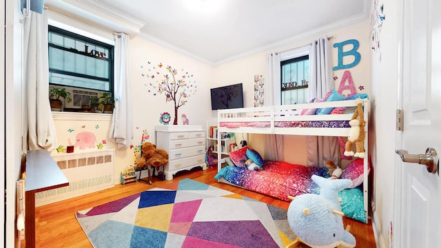 bedroom with multiple windows, ornamental molding, radiator, and hardwood / wood-style floors