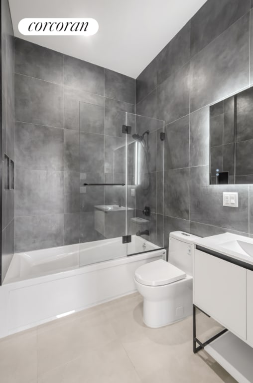 full bathroom featuring tile patterned flooring, vanity, shower / washtub combination, tile walls, and toilet