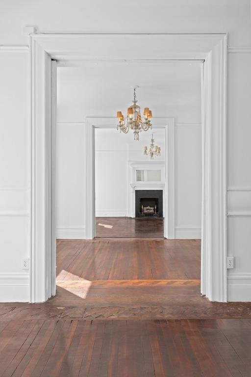 unfurnished living room featuring dark hardwood / wood-style flooring and a notable chandelier