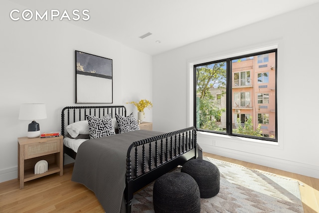 bedroom with light wood-style flooring, visible vents, and baseboards