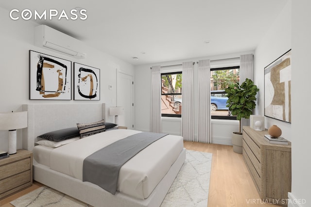 bedroom with light wood-type flooring and a wall mounted AC