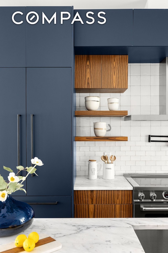 kitchen with decorative backsplash, light stone counters, black range with electric stovetop, blue cabinets, and open shelves