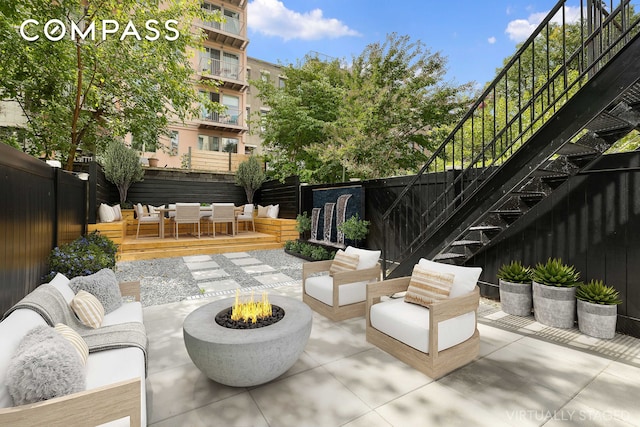 view of patio / terrace featuring a wooden deck, a fenced backyard, and an outdoor living space with a fire pit