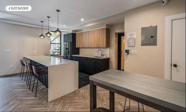 kitchen with black fridge, light countertops, a kitchen bar, visible vents, and electric panel