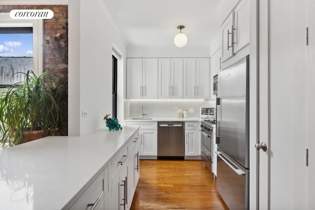 kitchen featuring decorative backsplash, light countertops, white cabinets, a sink, and premium appliances
