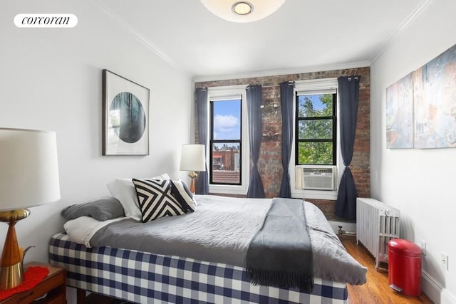 bedroom with visible vents, wood finished floors, cooling unit, radiator heating unit, and ornamental molding