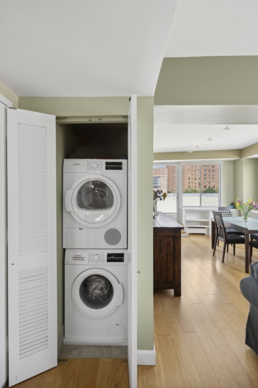 laundry area featuring light hardwood / wood-style flooring and stacked washer and clothes dryer