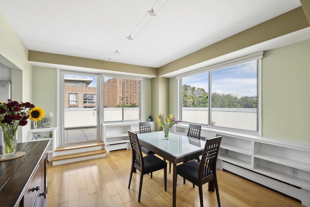 dining space with a baseboard heating unit, a baseboard radiator, and light wood-style flooring