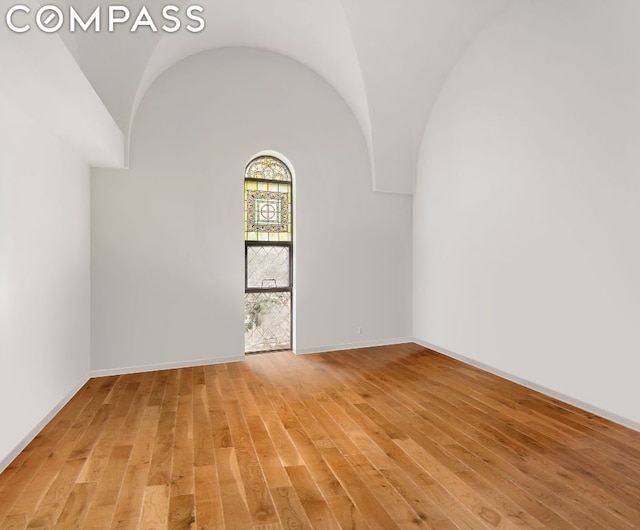 empty room with vaulted ceiling and light hardwood / wood-style flooring