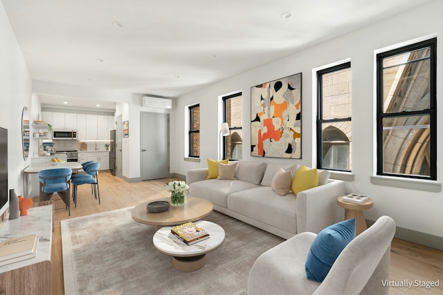 living area with recessed lighting, light wood-style floors, baseboards, and a wall mounted AC