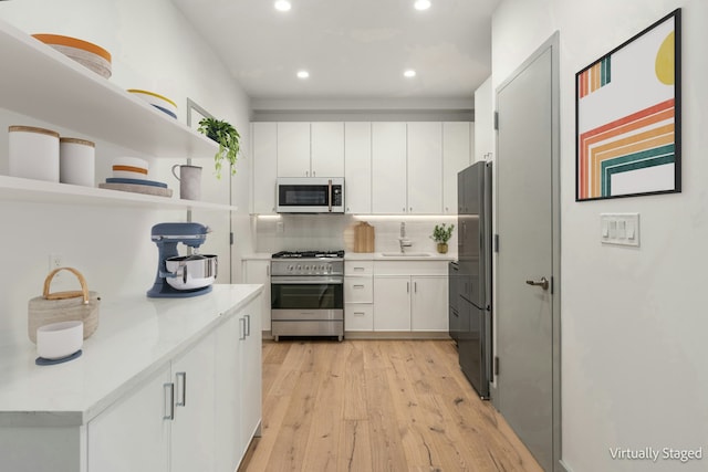 kitchen with open shelves, a sink, freestanding refrigerator, stainless steel stove, and white microwave