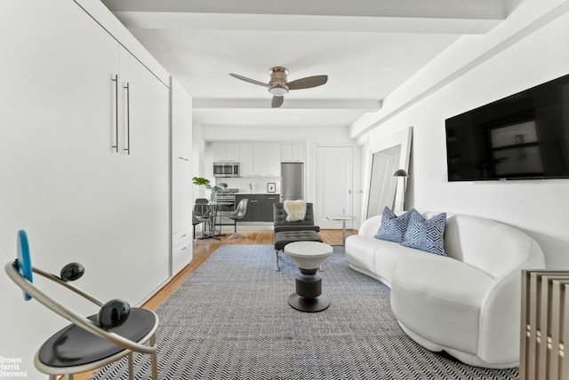 living room with ceiling fan, beam ceiling, and light hardwood / wood-style flooring