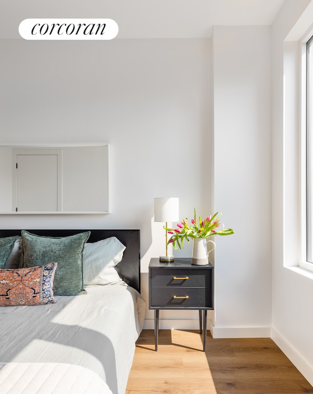 bedroom featuring wood finished floors, baseboards, and multiple windows