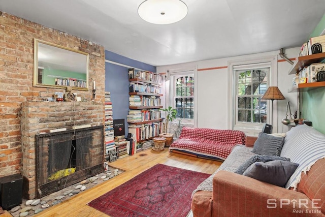 living room with a brick fireplace and hardwood / wood-style flooring