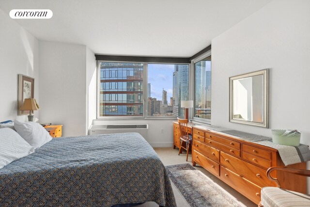 30 W St Unit 33B, New York City, NY 10004 - bedroom featuring light carpet, an AC wall unit, a view of skyline, and baseboards