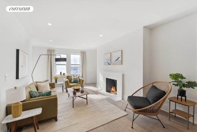 living room with visible vents, recessed lighting, a lit fireplace, and wood finished floors