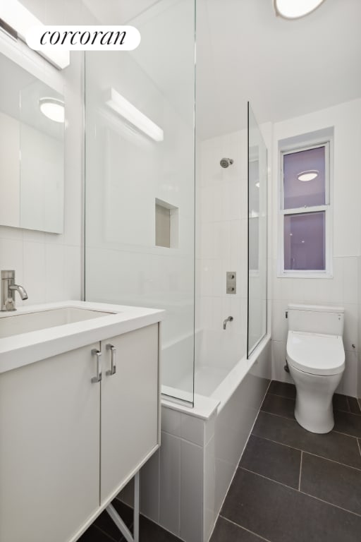 full bathroom featuring toilet, vanity, tile patterned flooring, tile walls, and tiled shower / bath