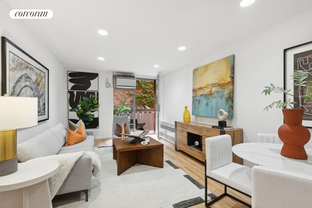 living room with light hardwood / wood-style floors and a wall unit AC