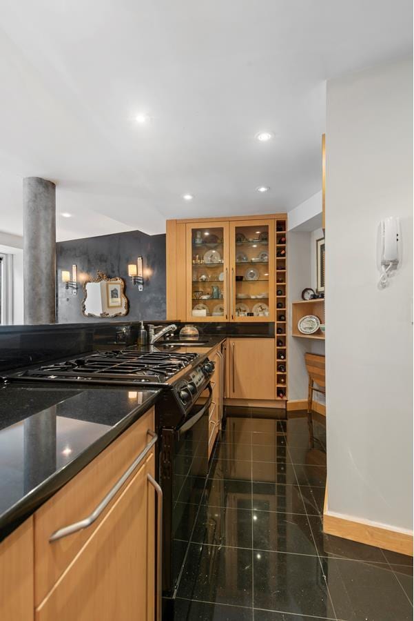 kitchen with baseboards, black gas range oven, glass insert cabinets, granite finish floor, and recessed lighting