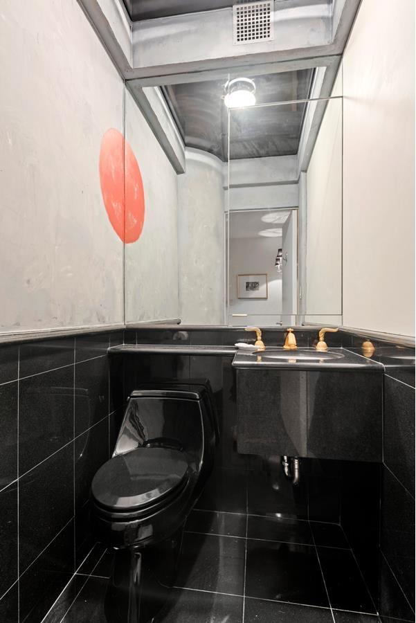 half bath featuring tile patterned flooring, toilet, visible vents, tile walls, and wainscoting