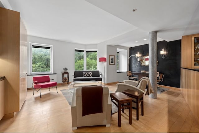 living room with light wood-type flooring, decorative columns, and baseboards