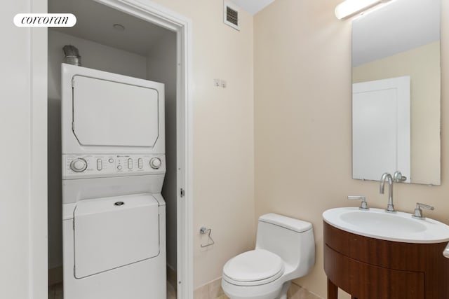 bathroom with vanity, stacked washer and dryer, and toilet