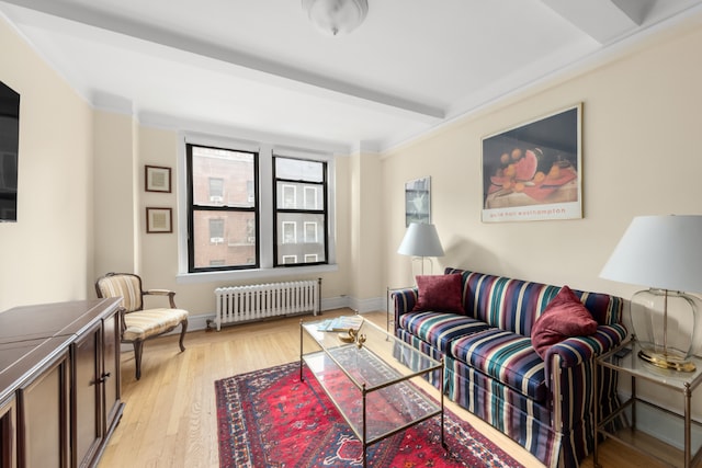 living area featuring light wood-type flooring, radiator, baseboards, and beam ceiling