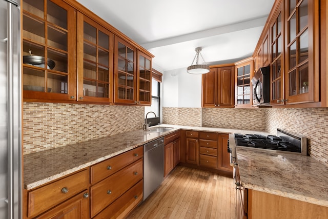 333 E 53rd St Unit 5Kl, New York City, NY 10022 - kitchen with stainless steel appliances, a sink, brown cabinets, backsplash, and light stone counters
