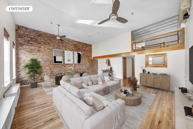 living area with visible vents, a ceiling fan, an AC wall unit, brick wall, and wood finished floors