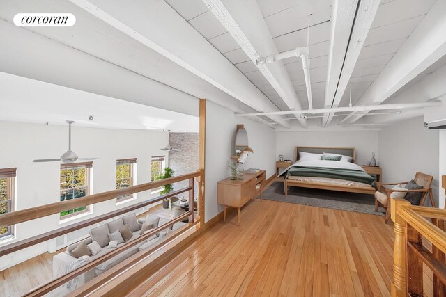 living room with ceiling fan, an AC wall unit, light hardwood / wood-style floors, a towering ceiling, and brick wall